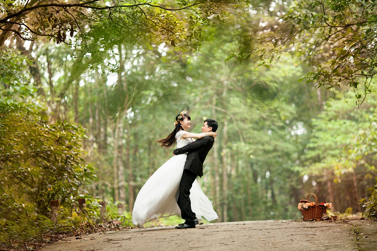 Image of a married couple dancing on a forest path, surrounded by flowers and trees