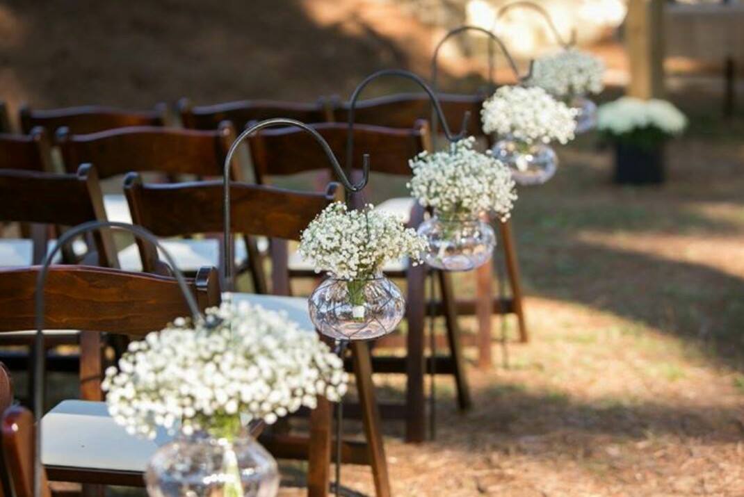 Outdoor setting with chairs and hanging flower vases for an event