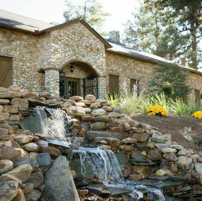 A stone house with a waterfall garden, blending nature and architecture to create a picturesque wedding venue. The waterfall adds a serene touch to the natural surroundings